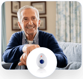 Elderly man in a blue sweater smilling and sitting on couch