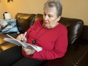 Senior lady with a remote patient writing in a spiral notebook