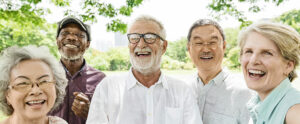 Five diverse seniors laughing outdoors