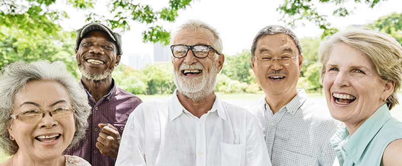 Five diverse seniors laughing outdoors