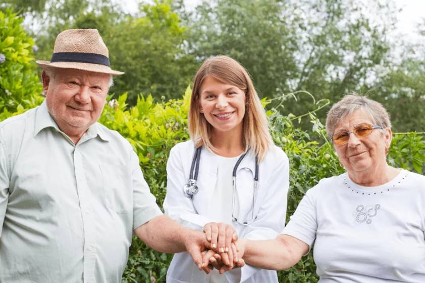 Female physician with stethescope holding a senior couple's hands