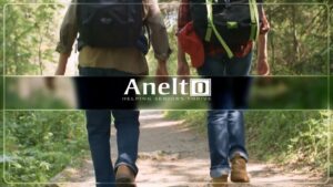 Two seniors walking a trail behind the Anelto logo